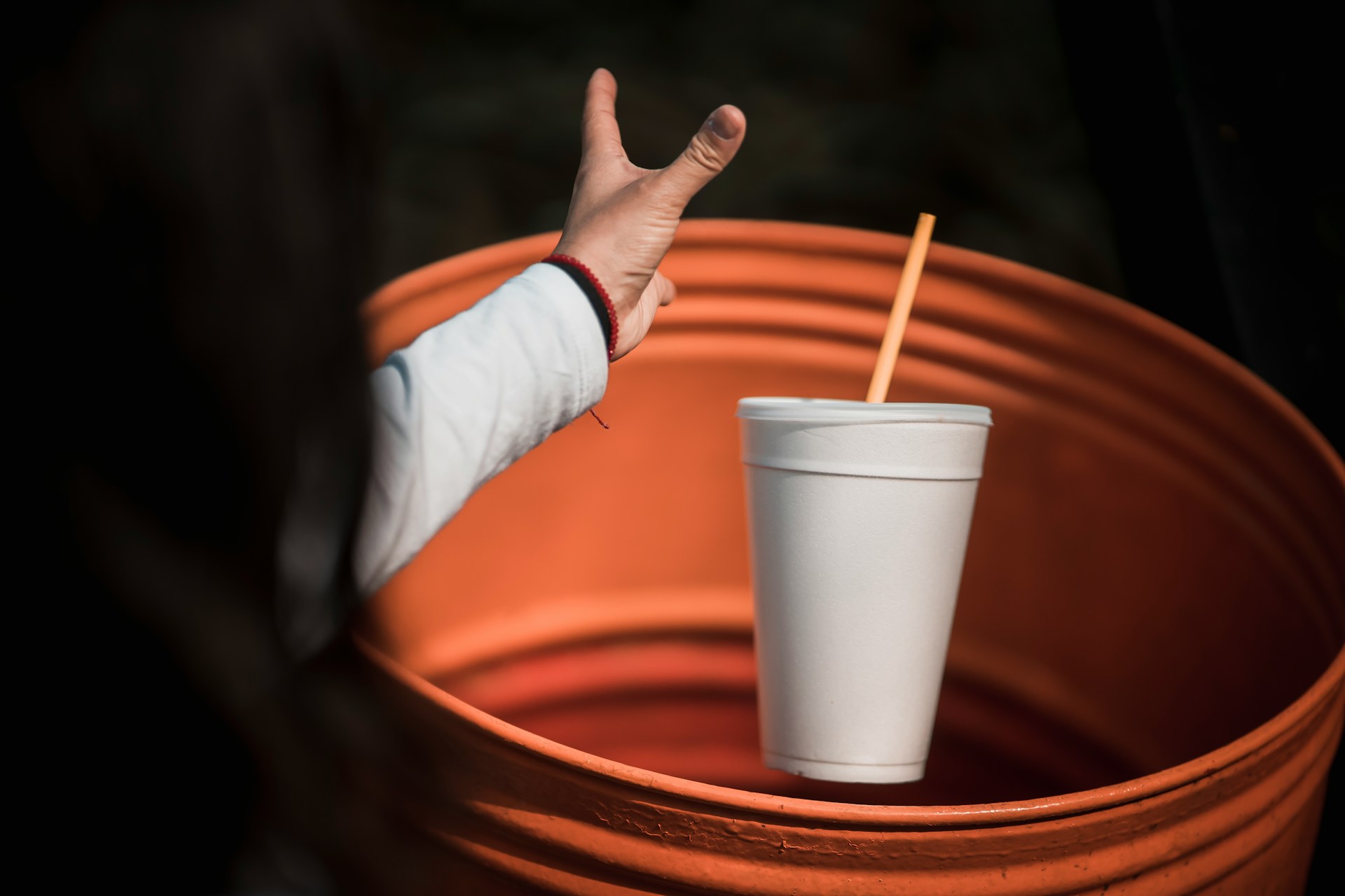 woman throwing away a styrofoam cup
